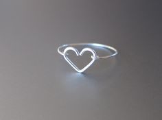 a heart shaped ring sitting on top of a gray surface with the word love written in it