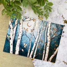 two cards with trees painted on them and one has the moon in the sky above it