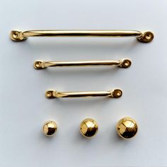 four gold colored handles and two knobs on a white surface with three balls in the middle