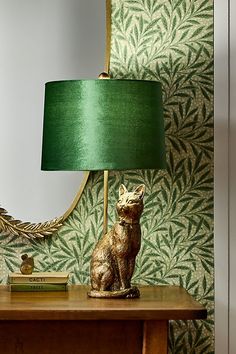 a cat lamp sitting on top of a wooden table next to a green lamp shade