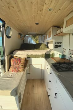 the interior of a camper van with wood flooring and white cabinets on both sides