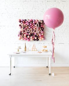 a table with balloons, cake and other items on it next to a brick wall