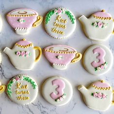 decorated cookies in the shape of teapots and kettles on a marble surface