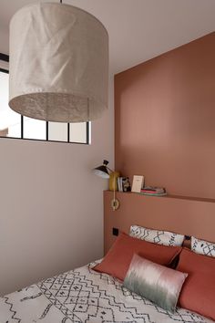 a bedroom with a bed, lamp and window in the corner that is painted pink