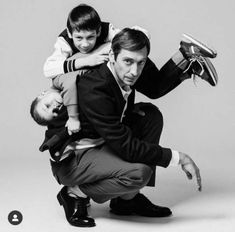 a man is holding two children while posing for a black and white photo with the child on his shoulders