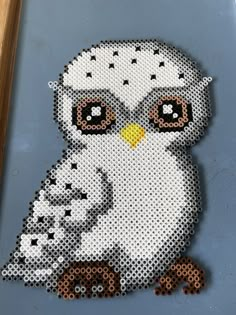 an owl made out of legos sitting on top of a blue surface with brown and white dots