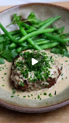 a plate with green beans and meat covered in gravy on top of it