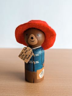 a small wooden toy with a red hat on it's head, holding a sign