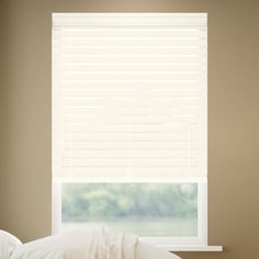 a white bed sitting under a window in a bedroom