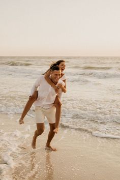 a man carrying a woman on his back at the beach