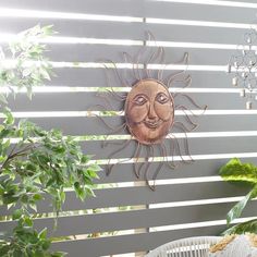 a metal sun face mounted to the side of a wall next to a potted plant