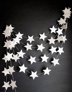 white stars hanging from strings on a black wall