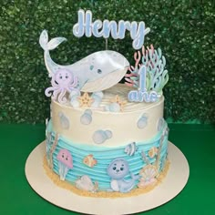 a blue and white cake with an ocean theme on it's side, sitting on a green table