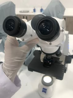 a close up of a person's hand holding a pair of microscopes in front of them