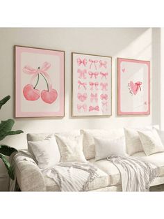 three framed pictures hang on the wall above a white couch in a living room with pink accents