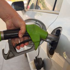 a person is pumping gas into a car at a gas station with green fuel nozzles