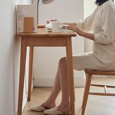 a woman sitting at a desk with a laptop and coffee cup in front of her