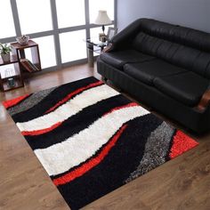 a living room with a black leather couch and red, white, and gray rug