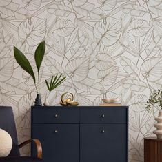 a living room with a blue cabinet and wallpaper that has plants on top of it