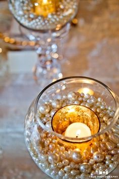 a candle that is inside of a glass bowl with pearls on the bottom and candles in it