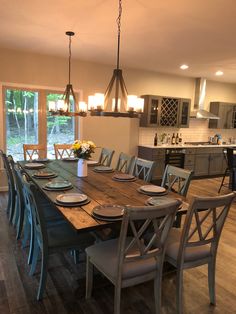 a dining room table with chairs and plates on it in front of an open kitchen