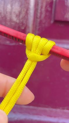 a person holding a pencil with a yellow rope attached to it