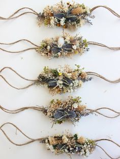 four dried flowers are arranged in rows on a white surface with jumbles of twine