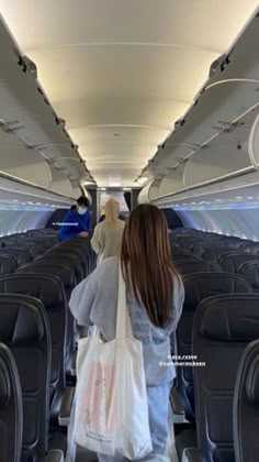 two people walking down an airplane aisle with bags on their backs and one person sitting in the aisle