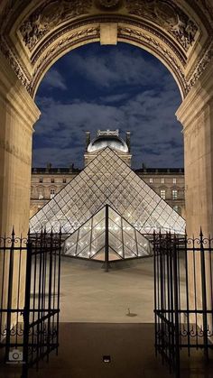 an arch leading into a building with a glass pyramid in the center and lights on it