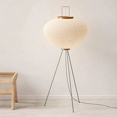 a white floor lamp sitting next to a wooden chair