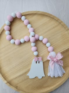 a wooden tray with a pacifier and necklace on it, next to a white ghost ornament