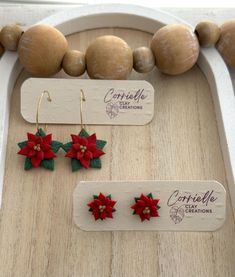 three pairs of earrings with poinsettia leaves on them sitting on a table