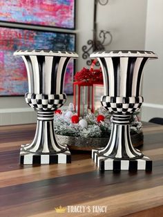 two black and white striped vases sitting on top of a wooden table