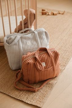 two bags sitting on the floor next to a crib