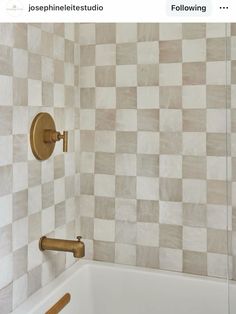 a bath tub sitting next to a white tiled wall with gold faucet handles