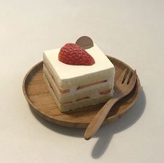 a piece of cake on a wooden plate with a fork and spoon next to it