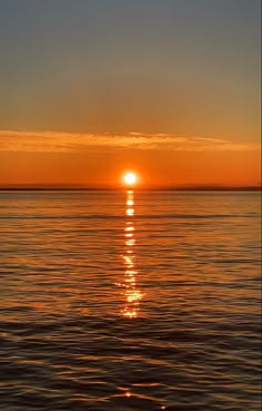 the sun is setting over the ocean with calm water