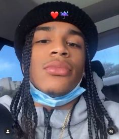 a man with dreadlocks wearing a hat and blue bandana in the back seat of a car