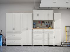 a garage with white cabinets and tools in it