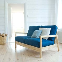 a blue couch sitting on top of a hard wood floor next to a white wall