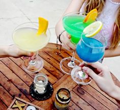 three people are holding up drinks on a table