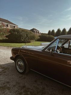 a brown car parked in front of a house on a driveway next to a green field