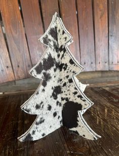 a black and white spotted christmas tree sitting on top of a wooden table