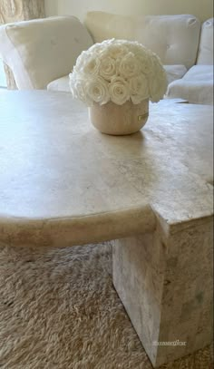 a vase with flowers sitting on top of a table in front of a white couch