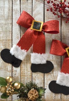 two christmas stockings are hanging on a wooden wall with ornaments around them and one is wearing a santa's hat