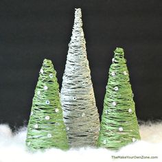 three small christmas trees made out of wire on top of white snow and black background