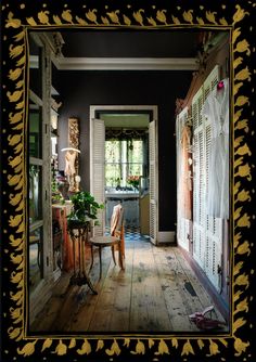 a room with wooden floors and black walls has an ornate frame around the doorway that is decorated with gold leaf trim