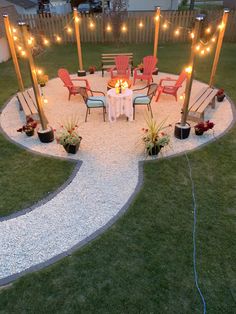 an outdoor dining area with chairs, lights and gravel path leading to the back yard