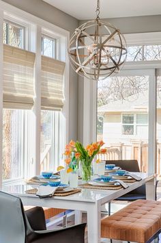 the dining room table is set with place settings for four people and has an orange tulip centerpiece