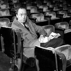 black and white photograph of man sitting in an empty auditorium